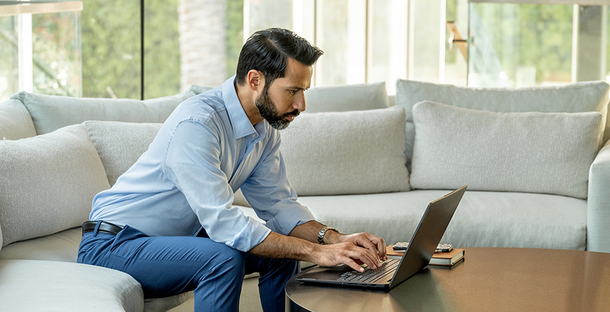 A man sitting on a couch, using his laptop.